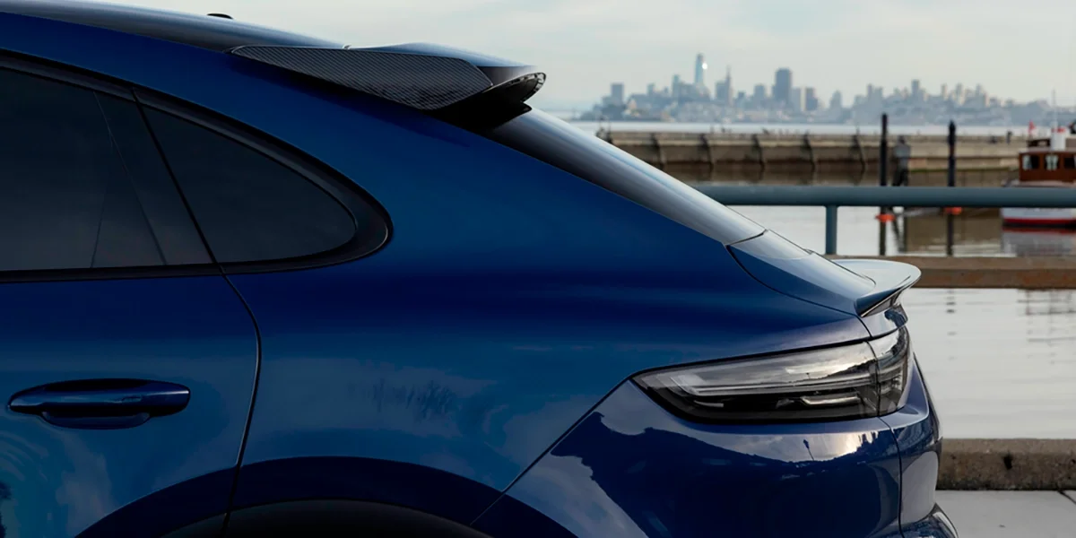 Blue Porsche Cayenne Turbo GT with carbon-fiber spoiler near the waterfront overlooking San Francisco skyline – Porsche Marin luxury SUV.